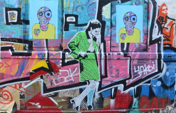 street art and graffiti on a wall, a woman in a green skirt suit and some creature's heads
