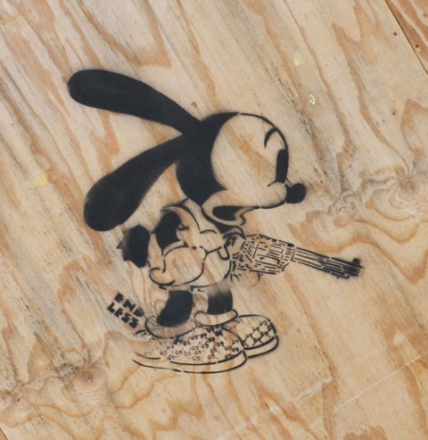 black stencil on wood of mickey mouse holding a revolver