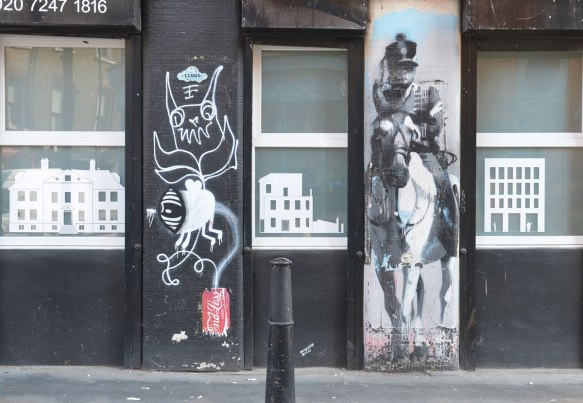 two vertical street art pieces on a black building, with windows on either side of them. one is a soldier on a horse and the other is a white drawing by endless 