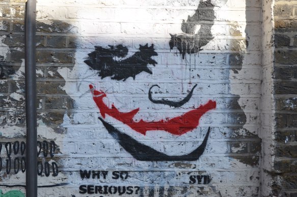 street art painting of the joker's face up close, bright red mouth, other features in black on white, with the words, Why so serious? bySyd 