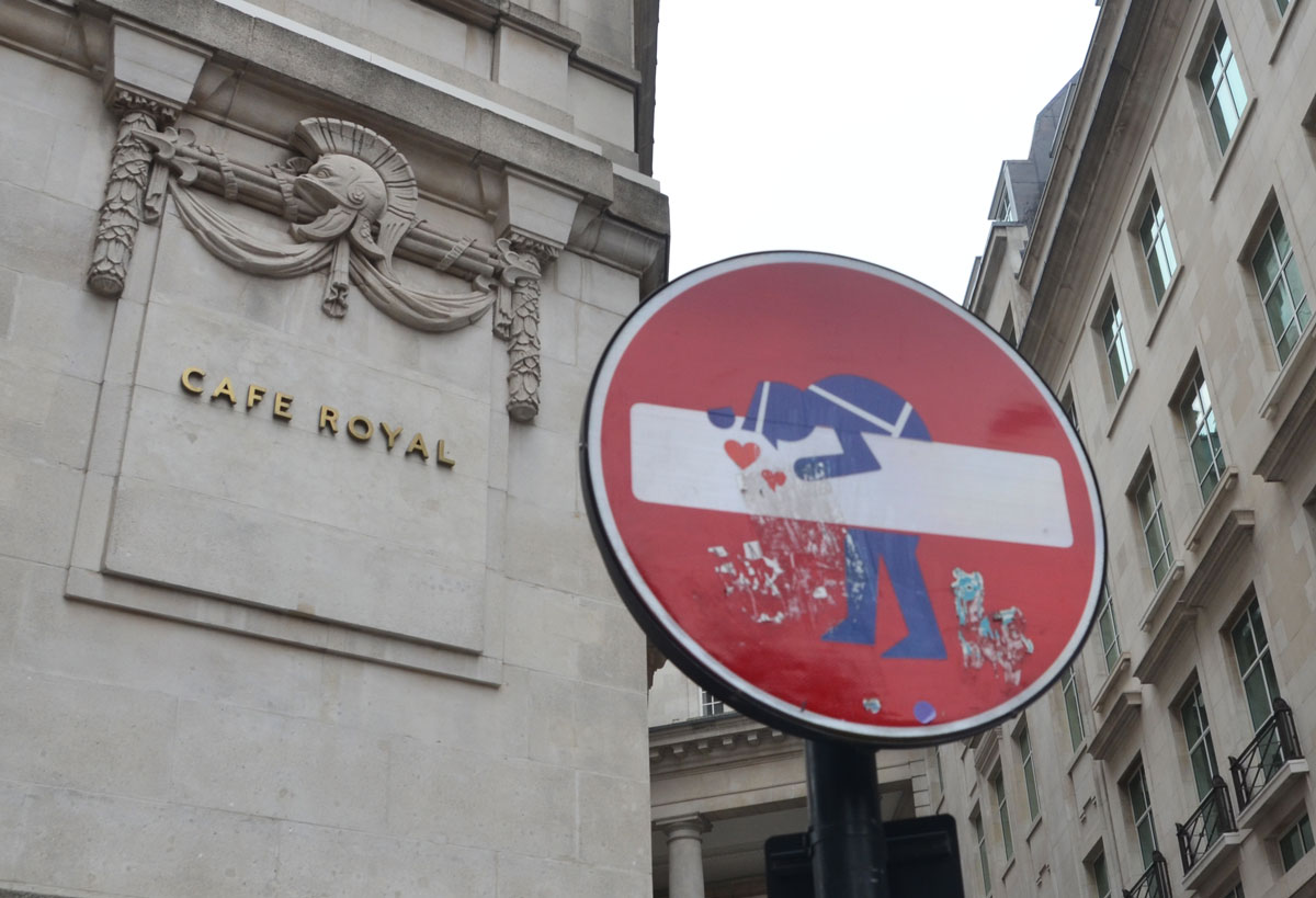 altered red and white no entry street sign - policeman kissing the bar 