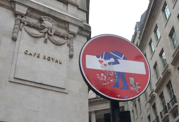 altered red and white no entry street sign - policeman kissing the bar 