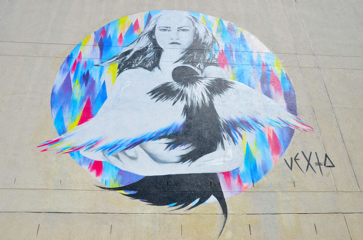a street art painting of a woman in a multicoloured background circle 
