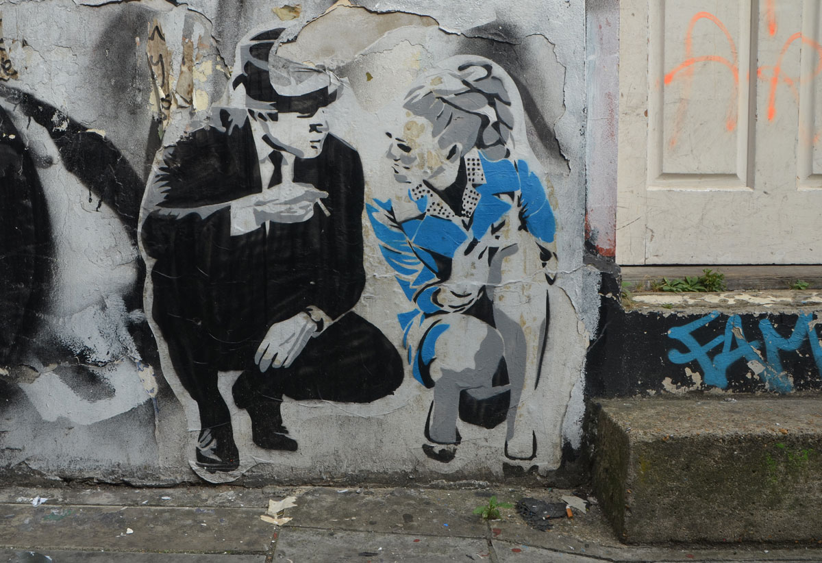 a paste up of a man and a woman squatting on one knee beside the front step of a door. They look like theyare talking to each other. 
