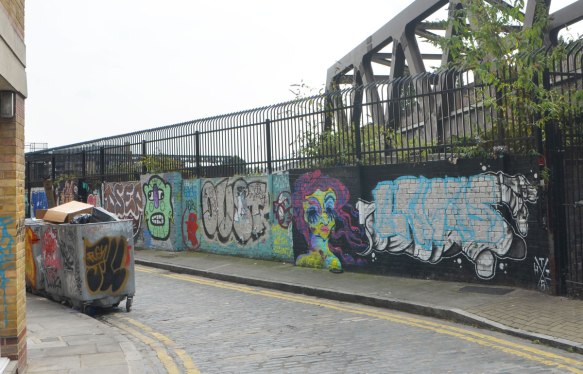 a view of the south side of Grimsbystreet, with a wall of graffiti between the road and the train tracks. 