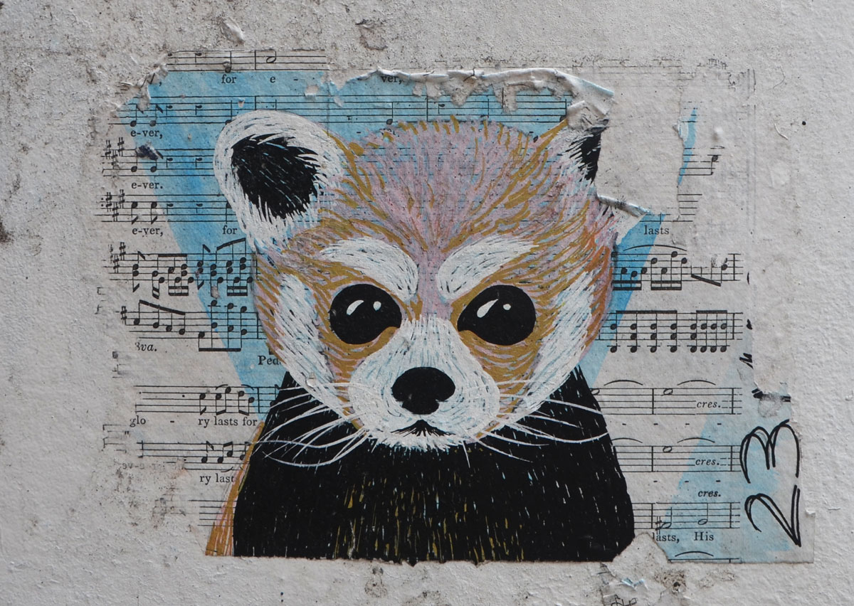 street art pasteup of the head of a little furry animal, painted on a piece of sheet music
