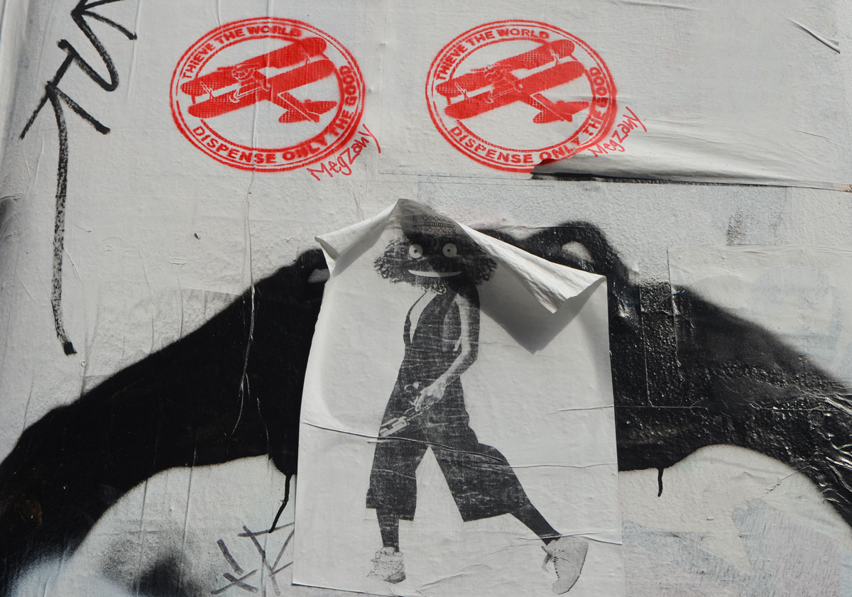 two red stencils of biplanes, with a paste up of a person's body, white sneakers on feet, but with muppet head. 