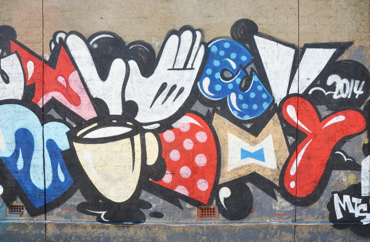 a mural featuring parts of Mickey Mouse and Minnie Mouse including a white glove, part of a bow, a bowtie