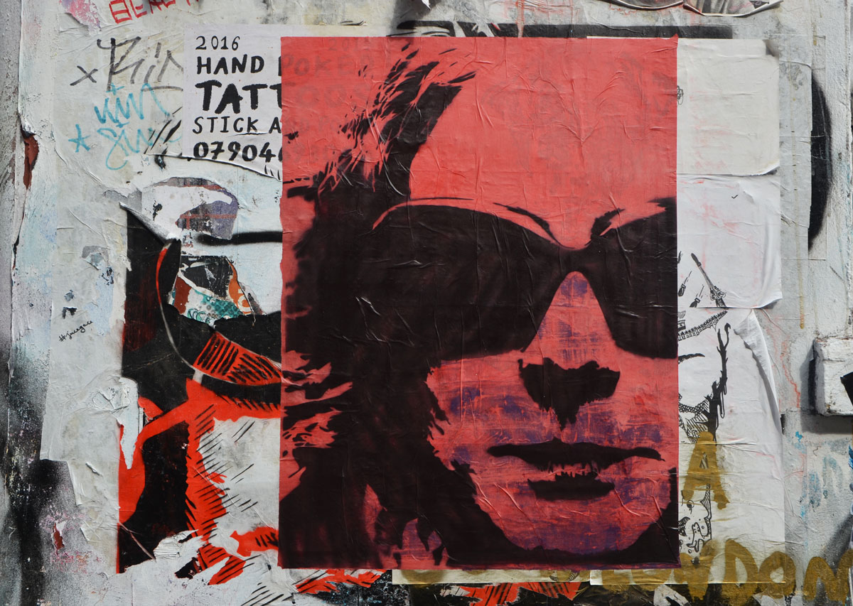 stencil, black on red of a face of a person wearing sunglasses. 