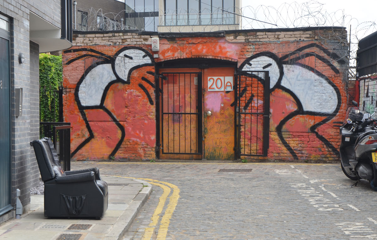 very large painting of two stick figures with white bodies, standing over the doorway of a building, and screaming at that doorway. 