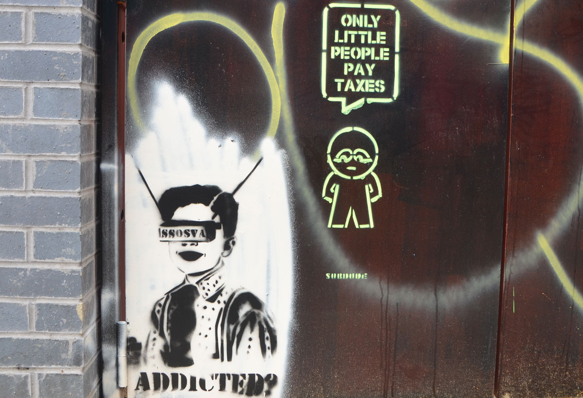 two pieces of street art, both stencils, First is a person with something in front of their face with the letters SSOSVA on it. The other is a surdude stencil of a little guy with the word bubble that says Only little people pay taxes. 
