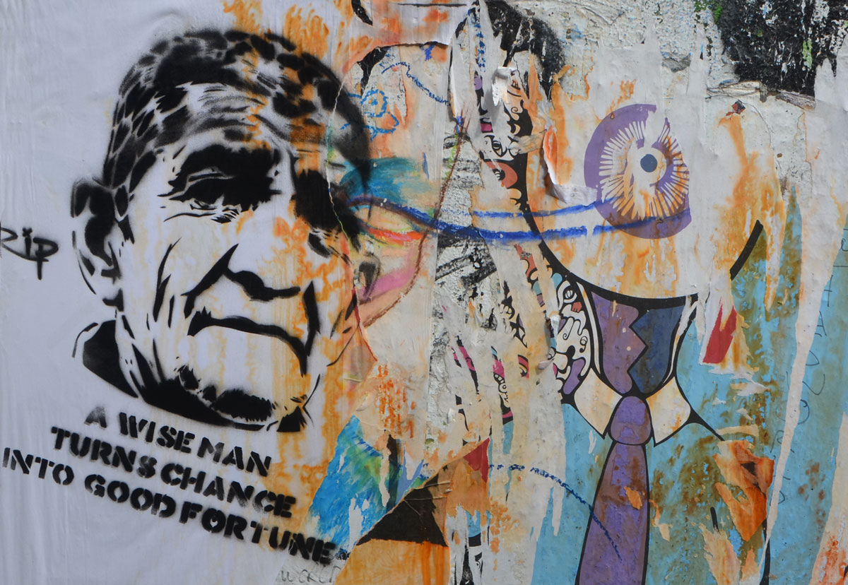 graffiti stencil of an older man's head with the words A wise man turns change into good fortune