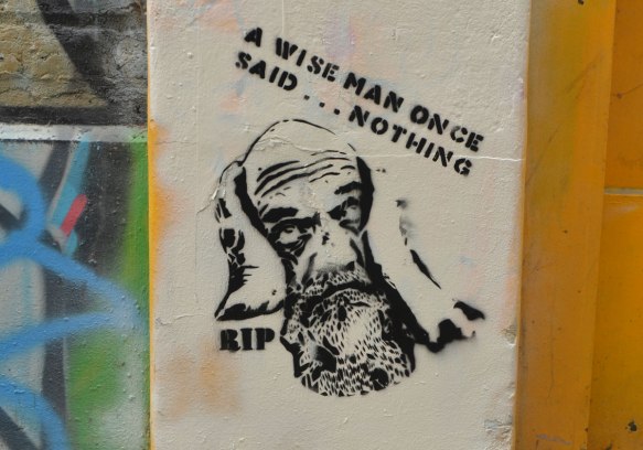 stencil of a bald man with a beard and one hand on his head, words that say A wise man once said nothing