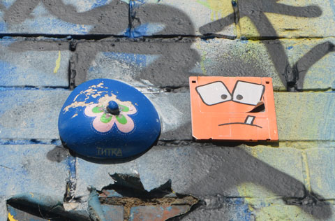 small 3D circle blue with flower in the center and an orange square beside the circle. The square has a face on it with square eyes