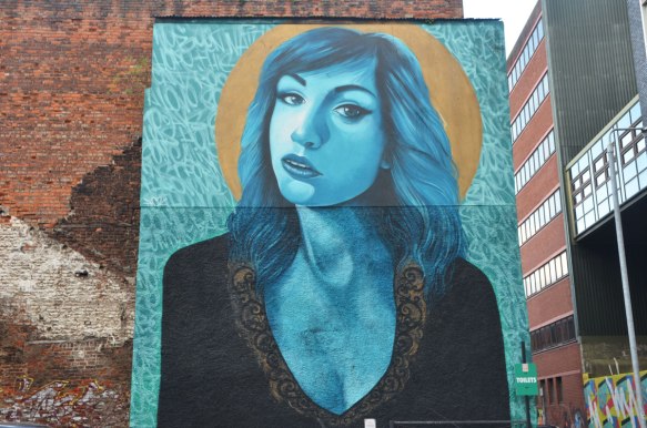 very large mural of a woman's upper body and head, done is shades of blue, shoulder length hair, looking at the viewer