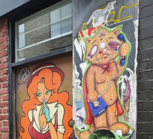 top part of a paste up by Saki & B along with a dagog cat upright on two legs, holding a phone and receiver. 