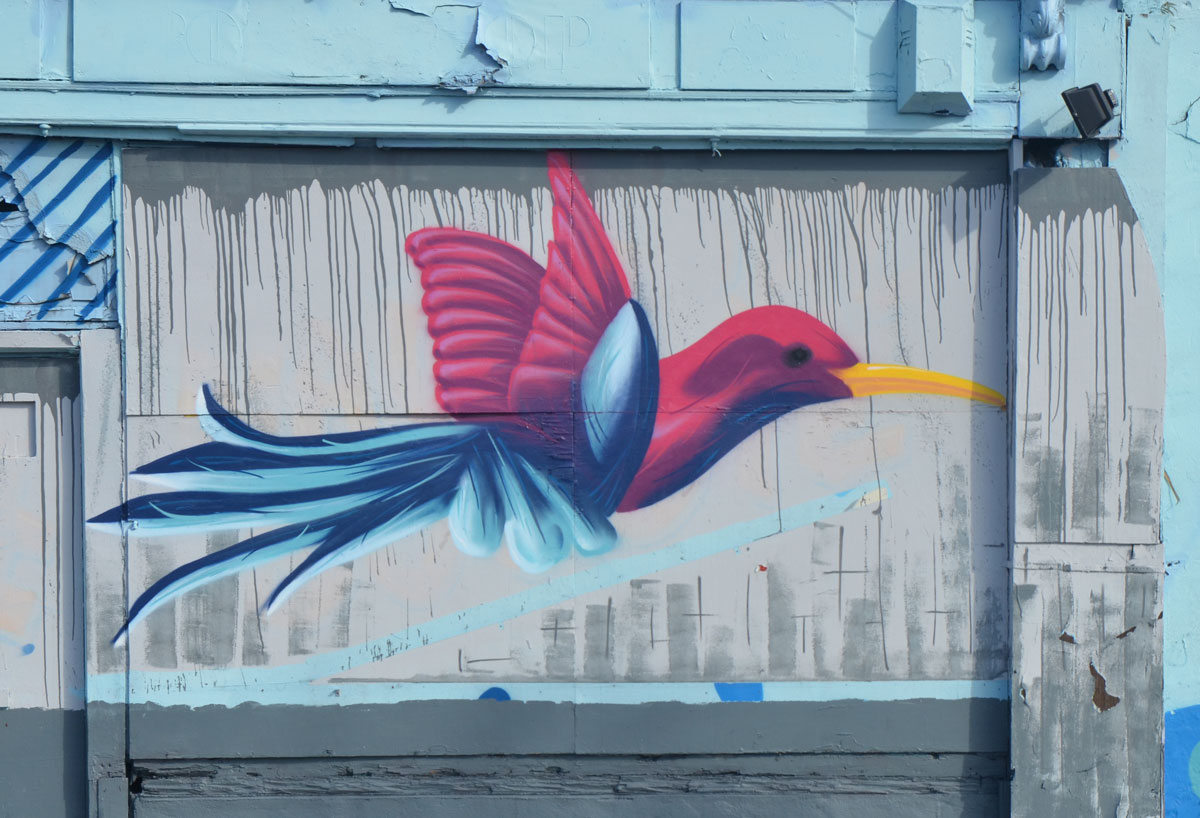 mural of a blue and dark pink bird in flight, with a long yellow beak