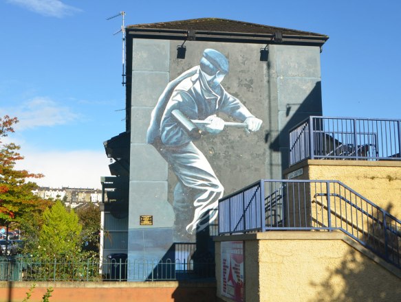 Free Derry mural in Bogside, Derry Northern Ireland, in shades of grey, commemorating Operation Motorman in 1971- a British soldier breaking down a door in Derry 
