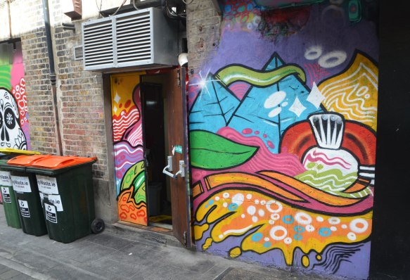 abstract painting street art on the side of a building and over the door, many colours and shapes