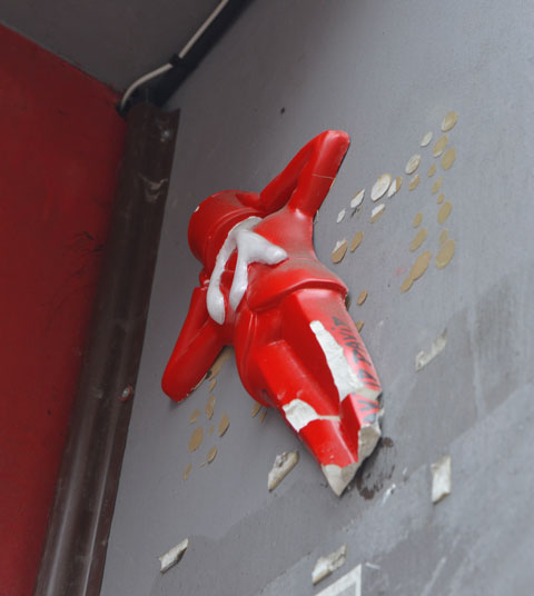 a 3 D figure in red attached high up on a wall 