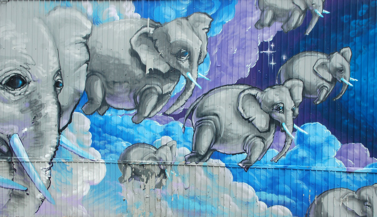 street art, graffiti, animals painted on a wall - elephants flying over blue and purple clouds and sky