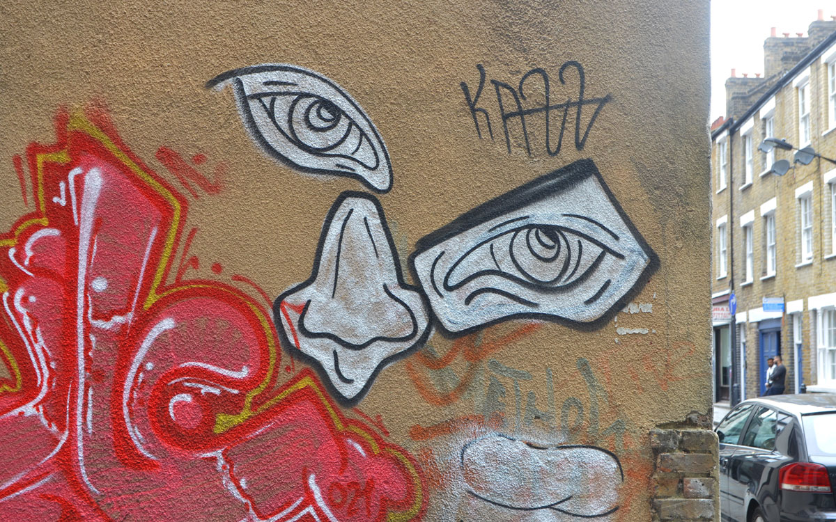 two large black and white eyes and a white nose with black outlines, painted on a wall. 