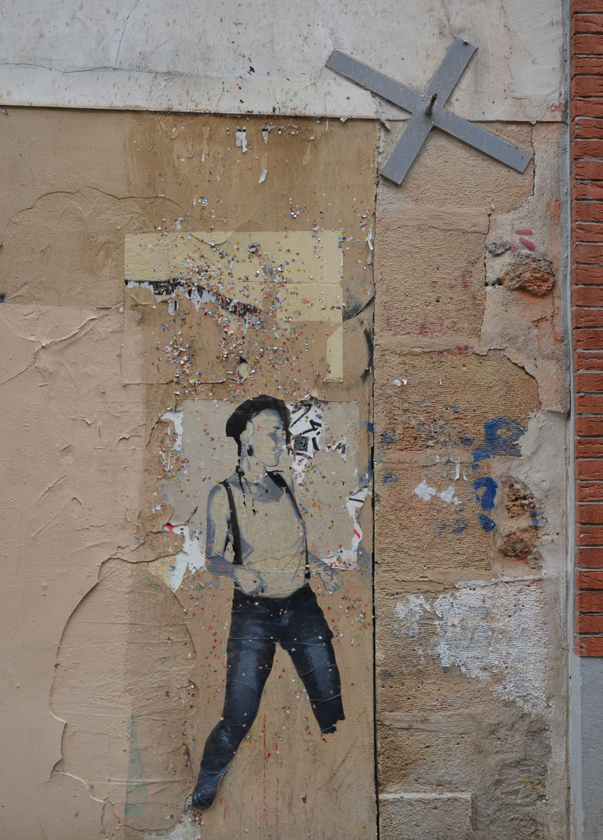 large size paper paste up of a young woman, standing, with a lot of small glittery pieces of paper scattered around her - wearing blue jeans and a white t-shirt 