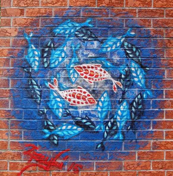 street art, graffiti, animals painted on a wall - a blue circle with concentric patterns of fish in reds, blues and blacks