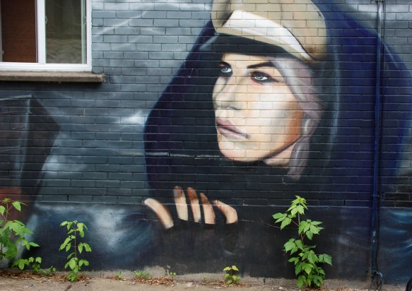 a realistic painting of a woman's head, wearing a black shawl, fingers also in the painting. 