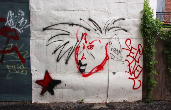 a quickly drawn face with wild spiky black hair. face in red. a red star to the bottom left