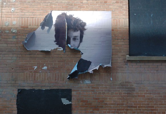 a paste up of a black and white photo of a young man that is torn and the bottom half is missing 
