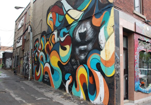 A man's face in grey tones surrounded by a rainbow coloured ribbon