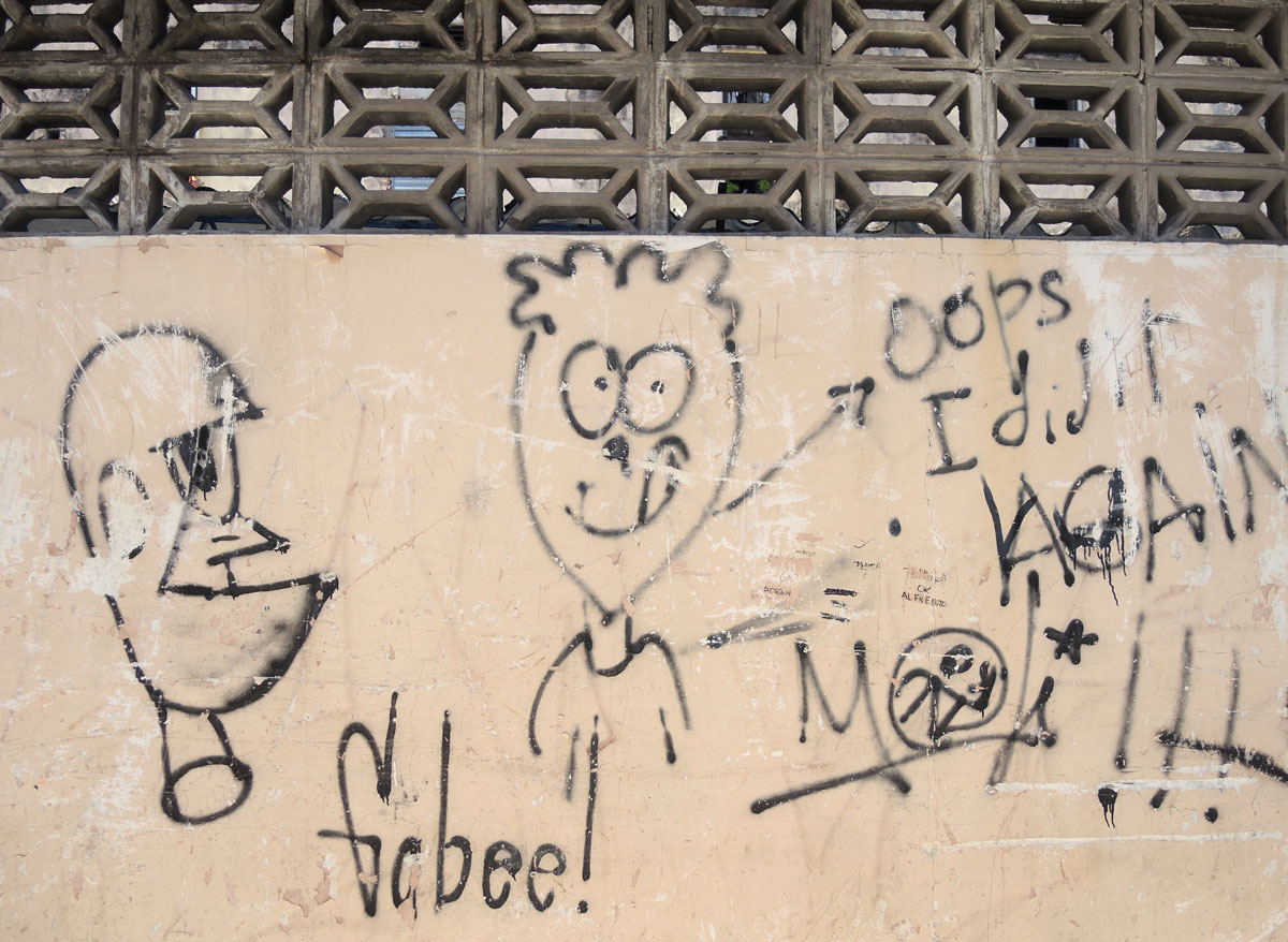 scribbled graffiti on a wall, a silly drawing of a boy with the words oops I did it again, some exclamation marks