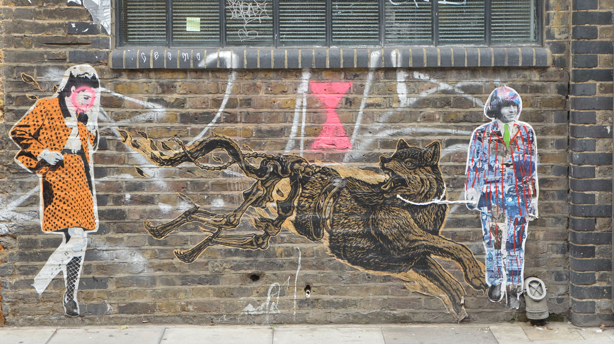 three large pasteups on a brick wall, a woman in an orange skirt and jacket by endless, a large growling dog who is running - head and front part of body are complete, back part of body is just the skeleton, and last is a man with longish hair, a multicoloured suit and a green tie. 