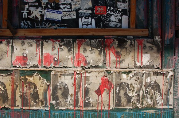 two rows of repeating posters. In browns, faded, with torn edges, and red paint blobs and drips on top of them. The top row is girl's head and the bottom is a young girl looking up 