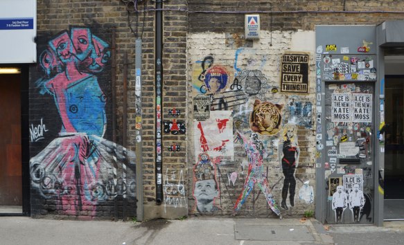 wall with lots of street art and graffiti, paste ups and posters 