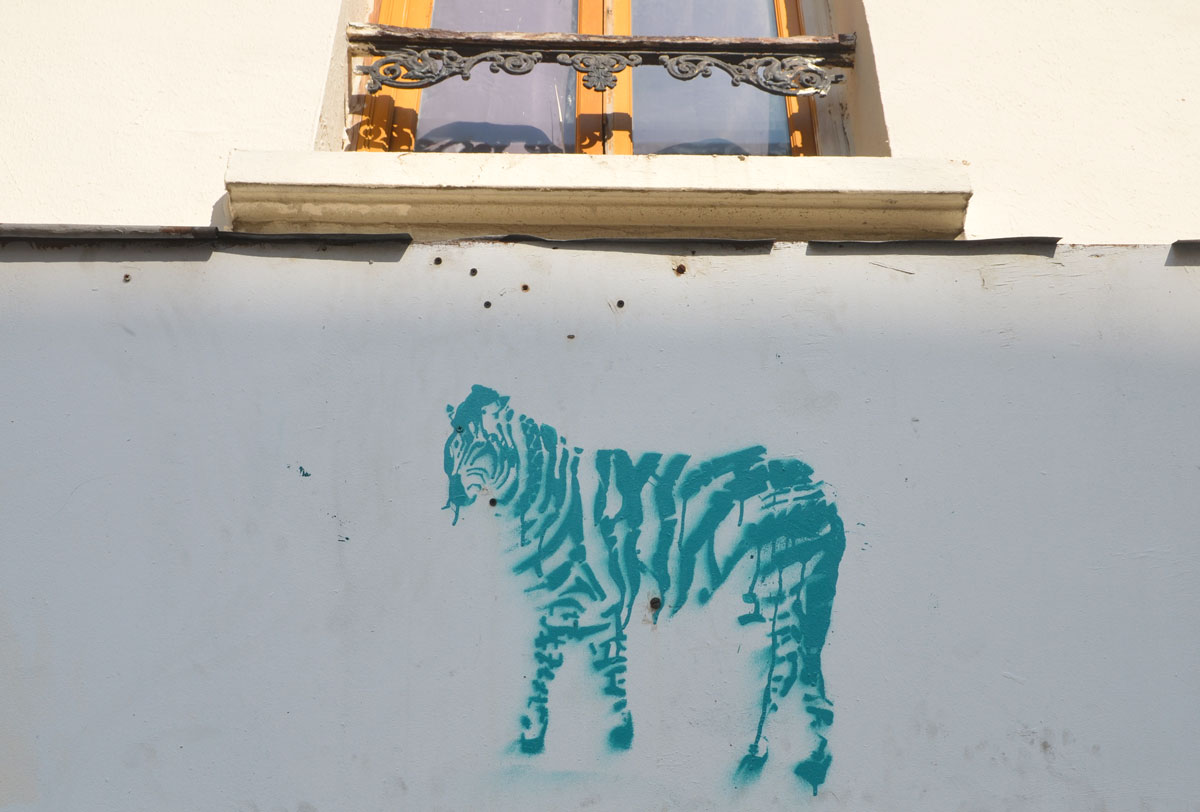 stencil graffiti of a greenish coloured striped zebra