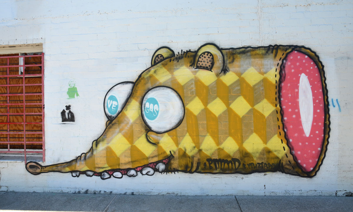 graffiti street art on a white wall - front end of yellow creature with big ping pong ball like eyes