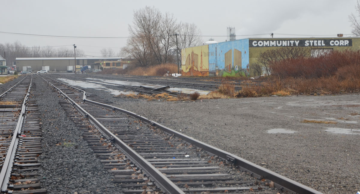 railway tracks run past the community steel corp building on Republic St., Buffalo. There is a mural on the side of the building. 