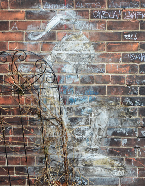 very faded street art piece of crouched young girl with a pony tail - although it is faded enough that I might be wrong. 