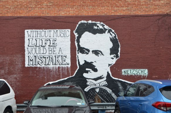 street art picture of Nietzsche head and shoulders in black and white along with a quote that says Without music life would be a mistake. 