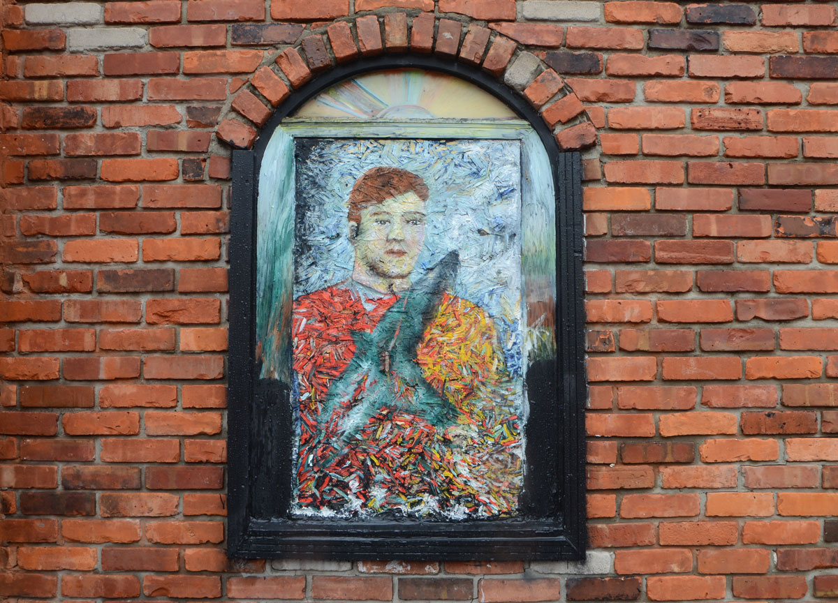 a painting of a man has been mounted in an arched window, covers the window. 