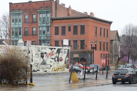 mural in the middle gound, two low rise buildings in the background, one is the Puritan building with green details around the windows in the front of the building. 