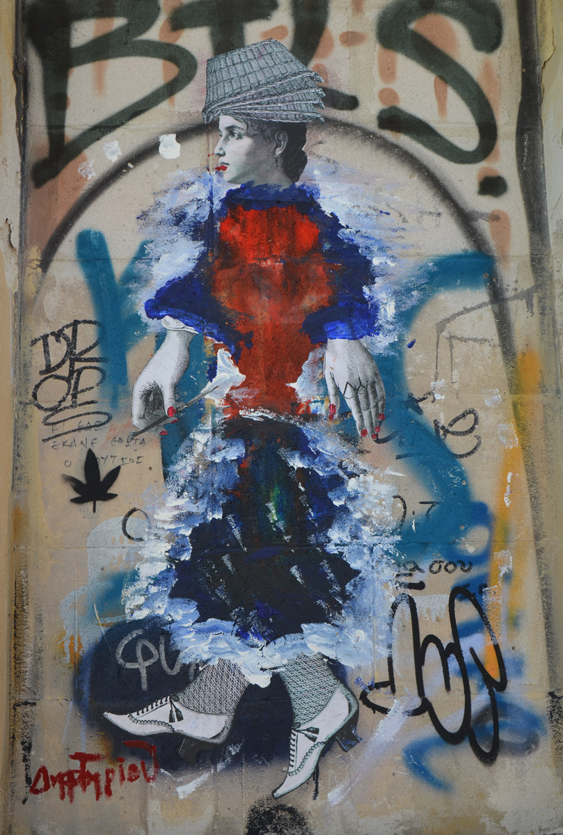 a black and white paste up of woman that has been painted over with many colours except for the head, hands and feet (wearing old fashioned shoes), on a wall in Athens,