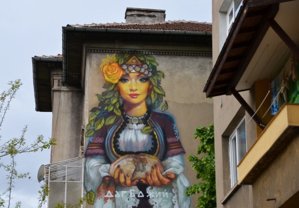 top part of mural by massimo, woman's upper body and head. she is holding a loaf of bread in her hands. 