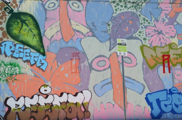stylized faces in pastel colours, at the edges of a tribute mural to reefa, painted by a number of different artists