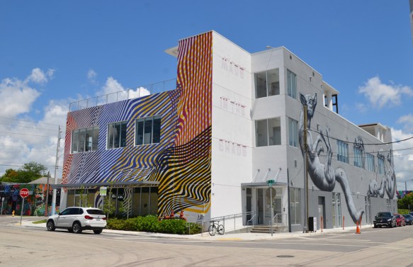 a building on a corner, a large mural by ROA on one side, lines in different colours on the other, and one wall with the words Made in the Shade 
