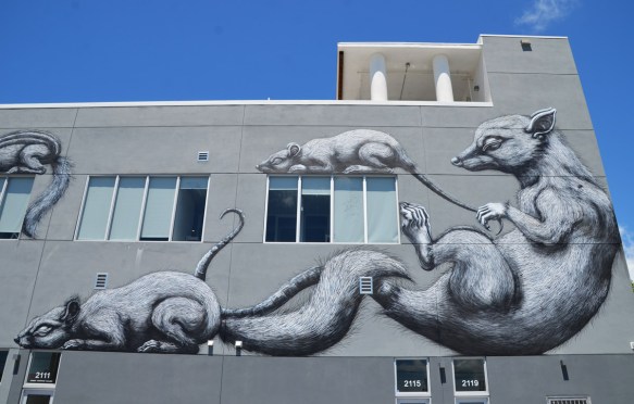  a large black and white mural on a grey building, by ROA, two adult animals and two babies 
