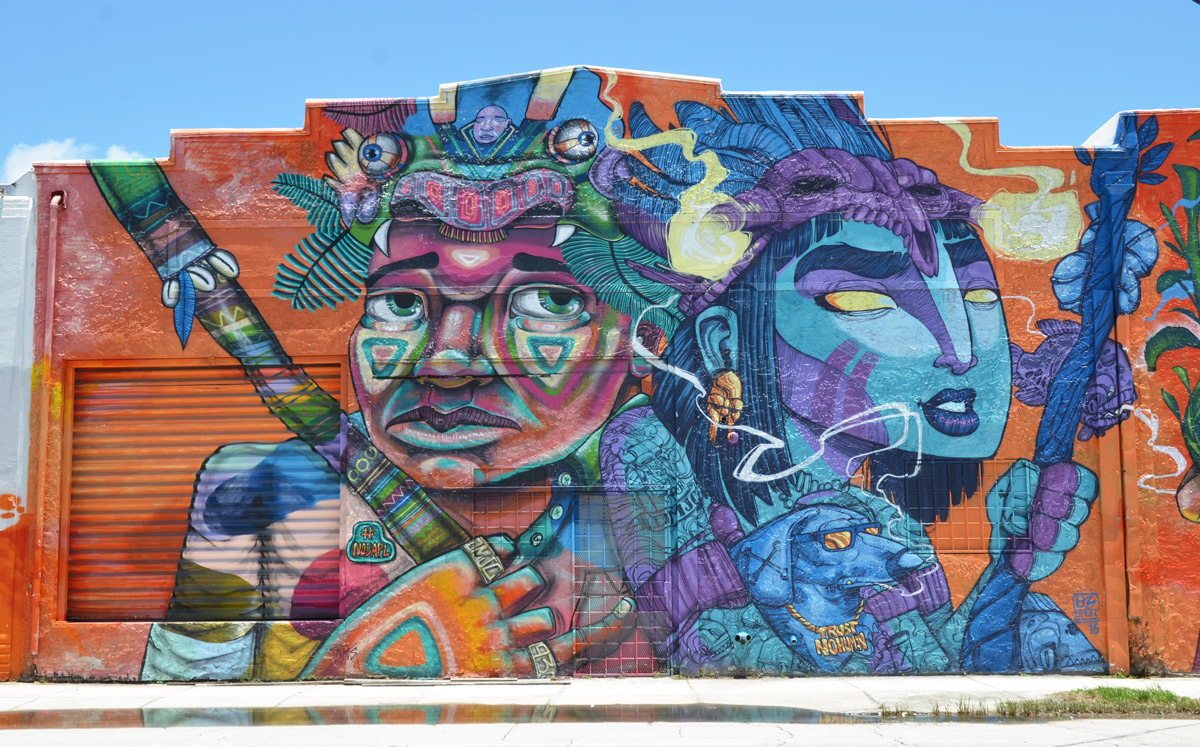 large mural, upper part of two people, one has face painted