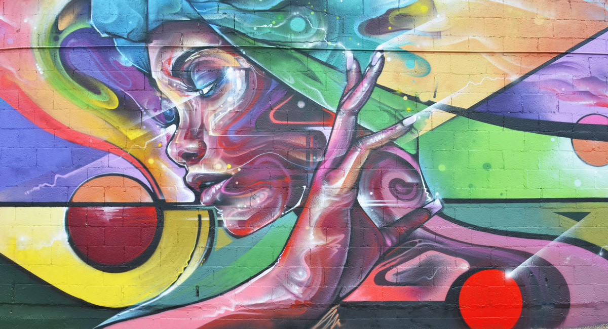 mural of woman's profile in purplish tones, green hair, also her hand is in the painting. a red circle on her left and her right. 